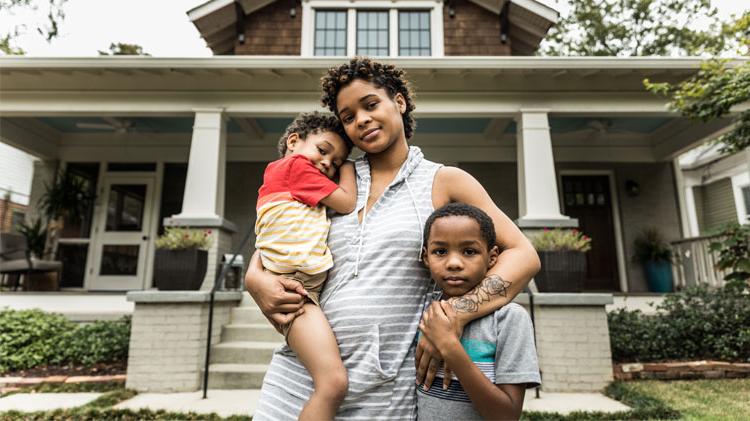 Portrait of a mother with her young children in front of a house. 